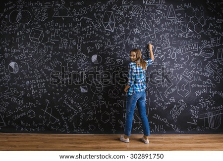 Beautiful young school girl in front of big blackboard