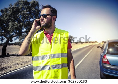 Man calling to insurance company by phone after a car breakdown.