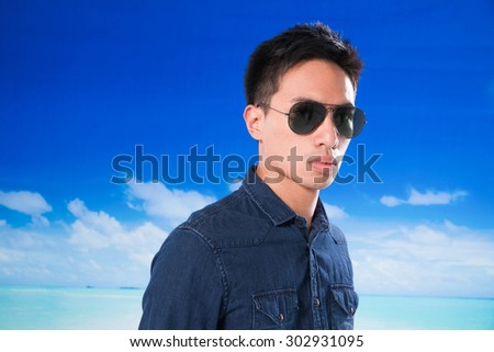 portrait of sunny man wearing sunglasses on a blue sky background