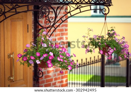 Front door is framed beautifully hanging flower pots with flowers