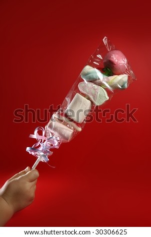 Candy colorful lollipop on child hand over red background