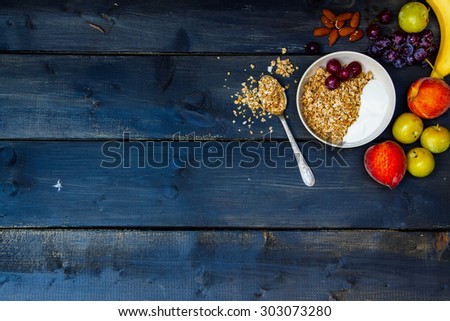 Breakfast with yogurt, fresh fruits, almonds and homemade granola on old wooden background with space for text. Health and diet concept. Royalty-Free Stock Photo #303073280