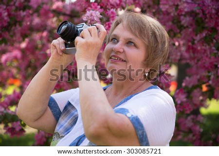 Senior Russian woman taking puctures in park