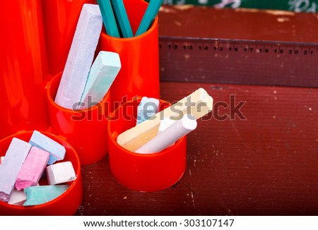 Colorful pencils of red yellow orange violet purple pink green and blue in stationary cup ruler and chalk on brown desk school background copyspace, horizontal picture