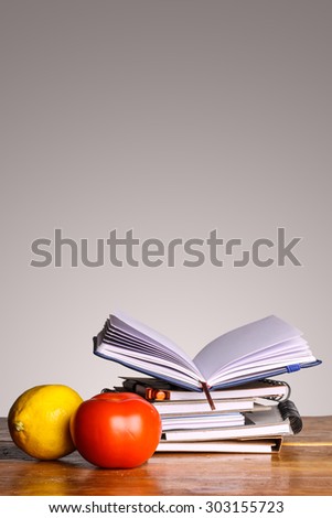 notebook with lemon and tomato infront on gray background
