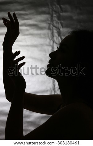 silhouette of woman in praising pose, low key