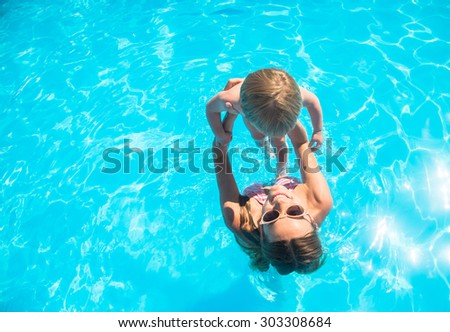 Young mother bathing in the pool with your child Royalty-Free Stock Photo #303308684