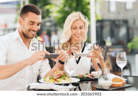 love, date, technology, people and relations concept - happy couple with smatphone taking picture of food at restaurant