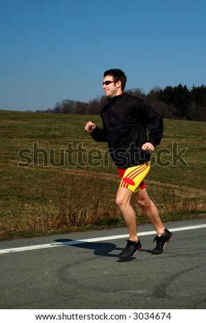 Photo of male runner running on a road.