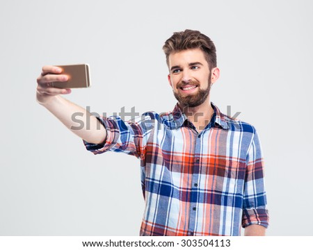 Portrait of a happy young man making selfie photo on smartphone isolated on a white background