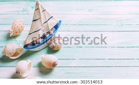 Decorative  sailing boat and marine items on wooden background. Sea objects on wooden planks. Selective focus. Place for text. Toned image.
