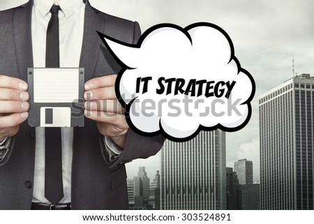 IT strategy text on speech bubble with businessman holding diskette on cityscape background