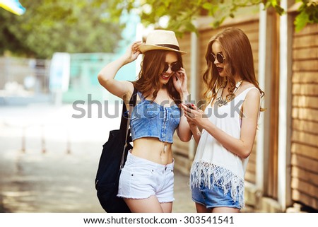 Two young beautiful girls are walking through the city and listen to music