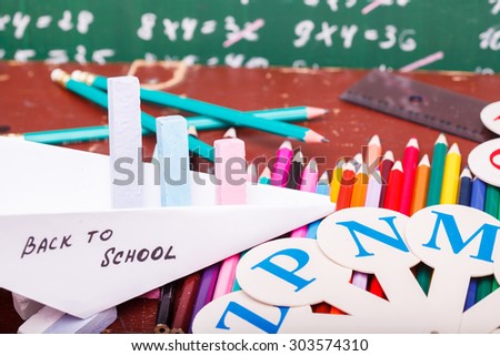 Colorful pencils of red yellow orange violet purple pink green and blue in stationary cup ruler fan english alphabet and paper plane with back to school text, horizontal picture
