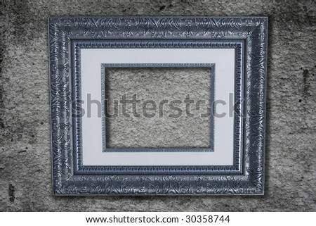 Wooden vintage picture frame hanging on a grey stucco wall.