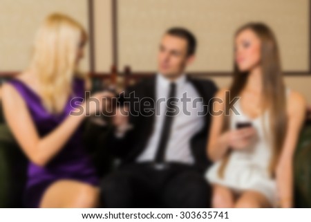 The company of people on a sofa talking. blurred Background