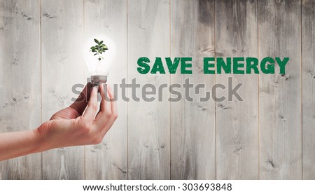 Hand holding environmental light bulb against wooden planks
