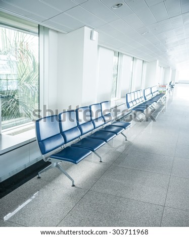Airport waiting area with rows of blue seats. Background for topics of travel and business.