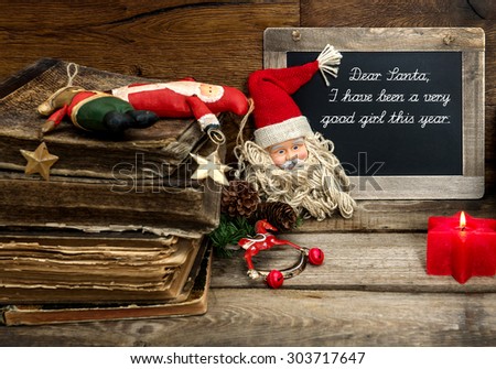 Christmas decoration with antique toys and red candle on wooden background. Vintage blackboard with sample text Dear Santa. Dark designed, selective focus
