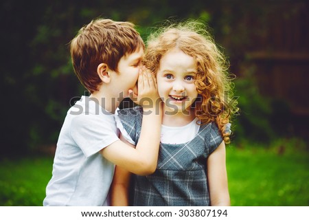 Little boy and girl whispers. Royalty-Free Stock Photo #303807194