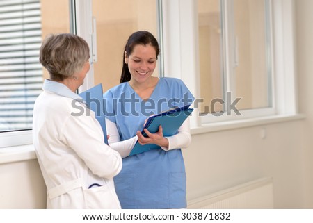 Two female doctors standing in hospital looking at patient files