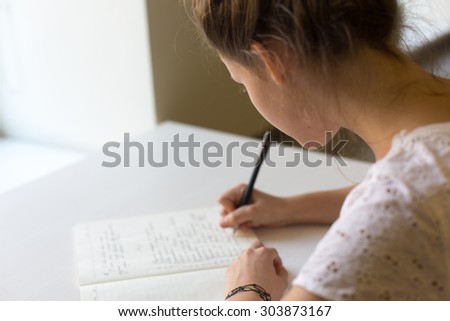 cute beautiful lonely teenager girl studying in the class writing down in her copybook
