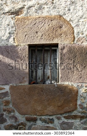 Old window with iron bars in stone wallc