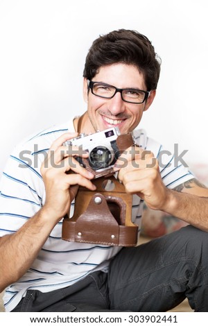 Young brunette man happy with a vintage photo-camera, taking photos