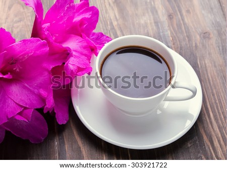 Cup of black coffee and pink flowers on the wooden table
