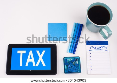Business Term / Business Phrase on Tablet PC - Blues, cup of coffee, Pens, paper clips Calculator with a blue note pad on White - White Word(s) on blue - Tax