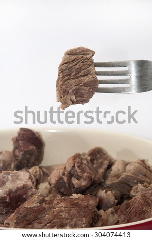 A piece of cooked beef impaled on a fork.