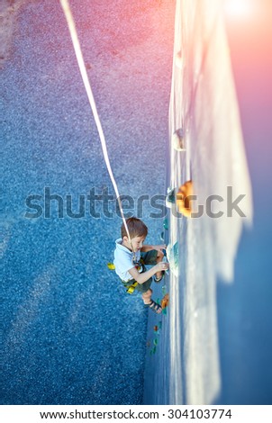 Little boy ascending in outdoor rock climbing gym