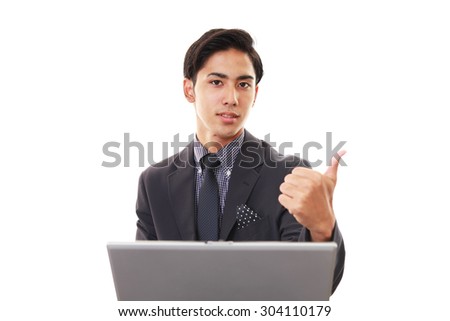 Business man at laptop, shows thumb up sign 