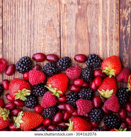 Mix of fresh berries closeup on rustic wooden background