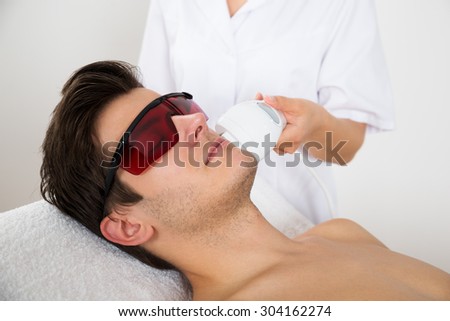 Young Man Receiving Laser Hair Removal Treatment At Beauty Center Royalty-Free Stock Photo #304162274