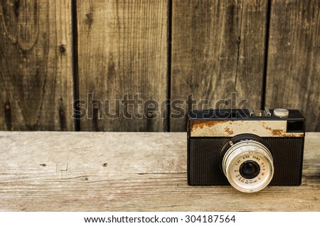 Retro camera on wood table background, old rust hue