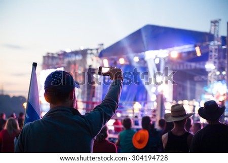 silhouette of young man; taking photo rock concert on the phone, open fest