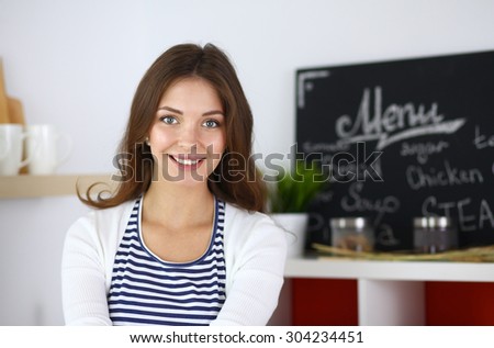 Young woman standing in kitchen at home .