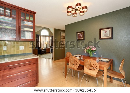Simple dinning area with connected kitchen and green walls.