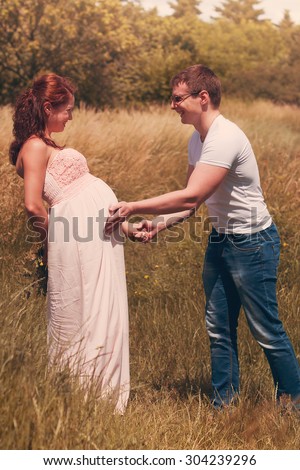 a married couple (husband and wife) is expecting a baby (pregnancy) in nature, walk