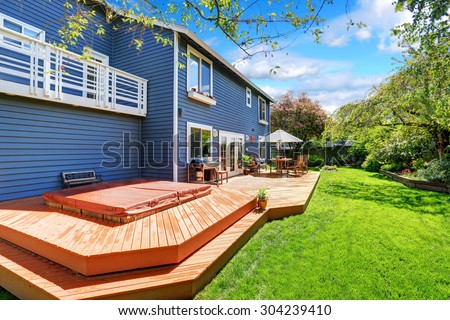 Picture perfect back deck with umbrella covered seats and lots of grass.