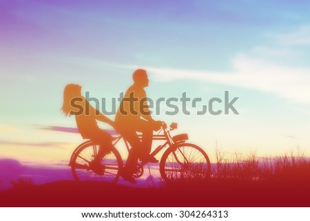 silhouette of sweet young couple in love happy time on bicycle