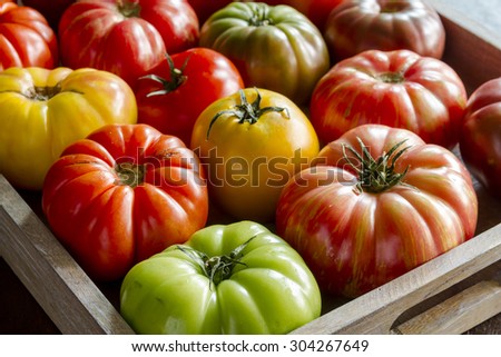 Wooden box filled with fresh vine ripened heirloom tomatoes from farmers market Royalty-Free Stock Photo #304267649
