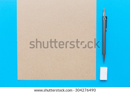 A white note book with lots of room for your text or image and a regular pencil and rubber on a wooden desk.
