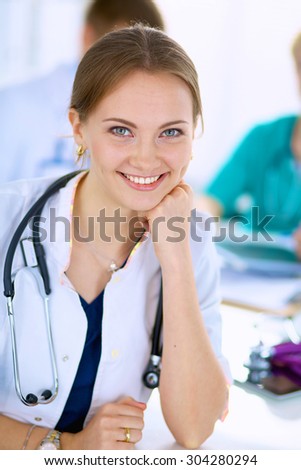 Beautiful young smiling female doctor sitting at the desk