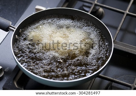 frying pan with boiling oil on the stove. Royalty-Free Stock Photo #304281497
