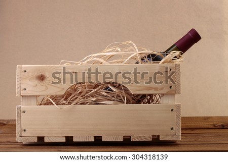 One glass wine corked new bottle full of alcohol red beverage wrapped in straw standing in wooden box on paper background copyspace, horizontal picture