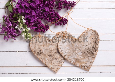 Fresh lilac flowers and decorative rustic hearts  on white painted wooden planks. Selective focus. 