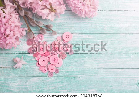 Postcard with heart from buttons and hyacinths and willow flowers  on turquoise painted wooden background. Selective focus. Place for text.