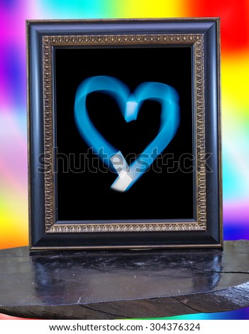 The Heart shape in Vintage picture frame on wood and on colorful background.
